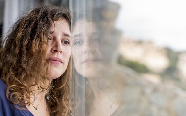 Mujer pensativa viendo hacia afuera de ventana