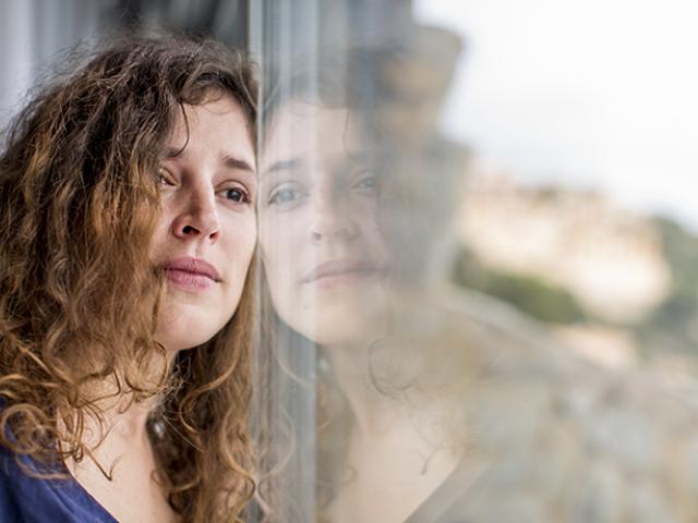 Mujer pensativa viendo hacia afuera de ventana